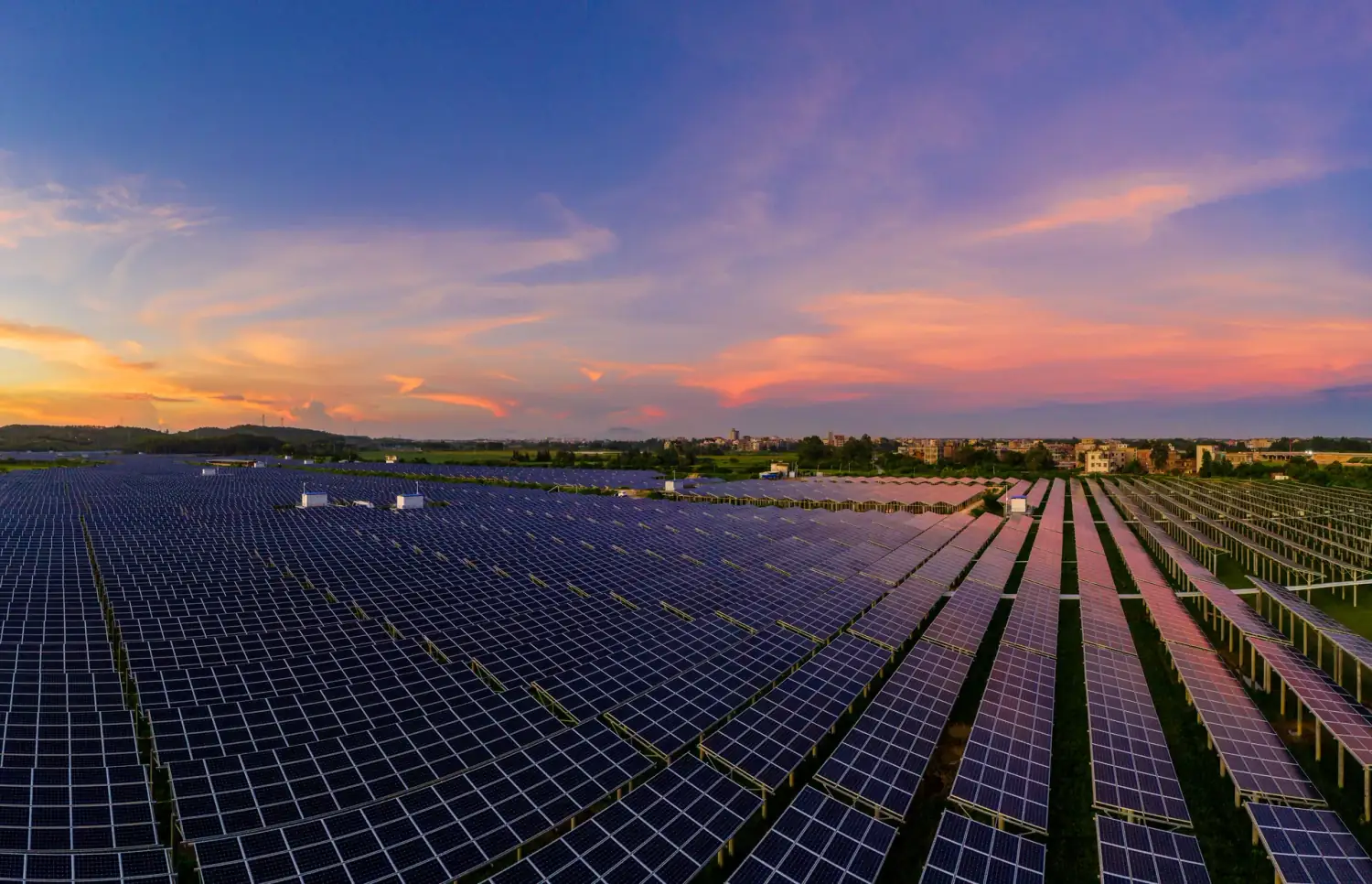 Solar panels beside cultivated land at sunrise